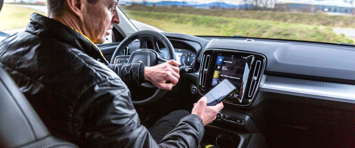 Autofahrer liest Nachricht auf Smartphone