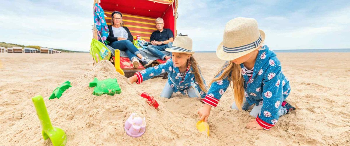 Kinder bauen Sandburgen vor einem Strandkorb in Trassenheide